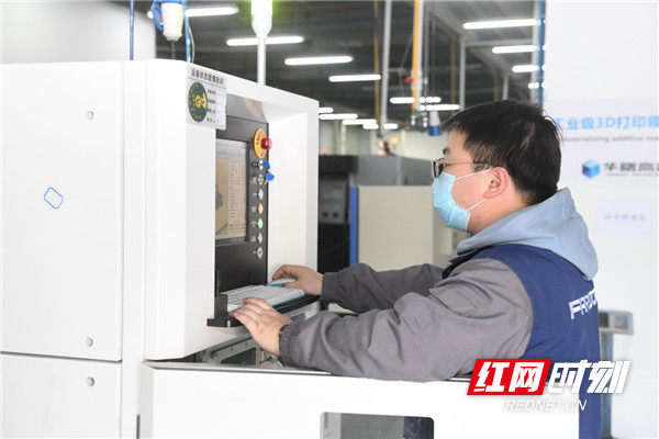 华曙高科应用部门员工正在操作调试3D打印设备。