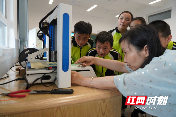 老师正在指导学生使用3D打印机。（图文/印斌 龙代军 章育鑫）