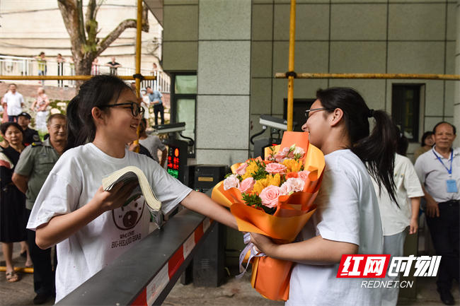 妹妹给刚高考完的姐姐献花，姐姐给妹妹送高考复习资料。（肖亚辉/摄）