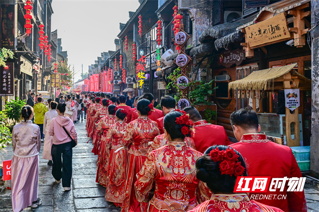 红灯笼沿青石板路次第排开,中国结在微风中摇曳……11月16日,随着三声震天鼓响,湖南省第十一届国潮集体婚礼在娄底新化县上梅古镇向东街启幕,100对身着传统喜服的新人携手踏过红毯,在千年古街的见证下许下相守承诺。