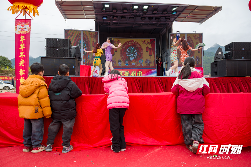 《戏台内外》新春时节,流动戏台搭进村头。厚实的冬装挡不住好奇,四个孩子并排踮脚张望,此刻,台上的热闹便是他们眼中最浓的年味。.jpg 《戏台内外》新春时节,流动戏台搭进村头。厚实的冬装挡不住好奇,四个孩子并排踮脚张望,此刻,台上的热闹便是他们眼中最浓的年味。.jpg