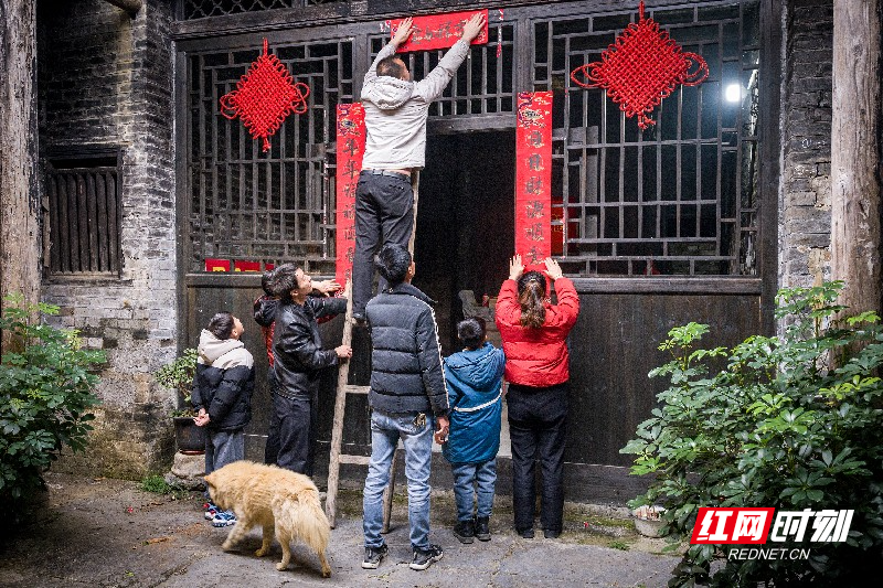 《红联映古宅》古宅门前,全家老小齐上阵贴春联。红绸结高悬,黄犬踱步,老少同心的忙碌瞬间,将传统年俗与阖家温情,深深镌刻在老宅的肌理之中。.jpg 《红联映古宅》古宅门前,全家老小齐上阵贴春联。红绸结高悬,黄犬踱步,老少同心的忙碌瞬间,将传统年俗与阖家温情,深深镌刻在老宅的肌理之中。.jpg